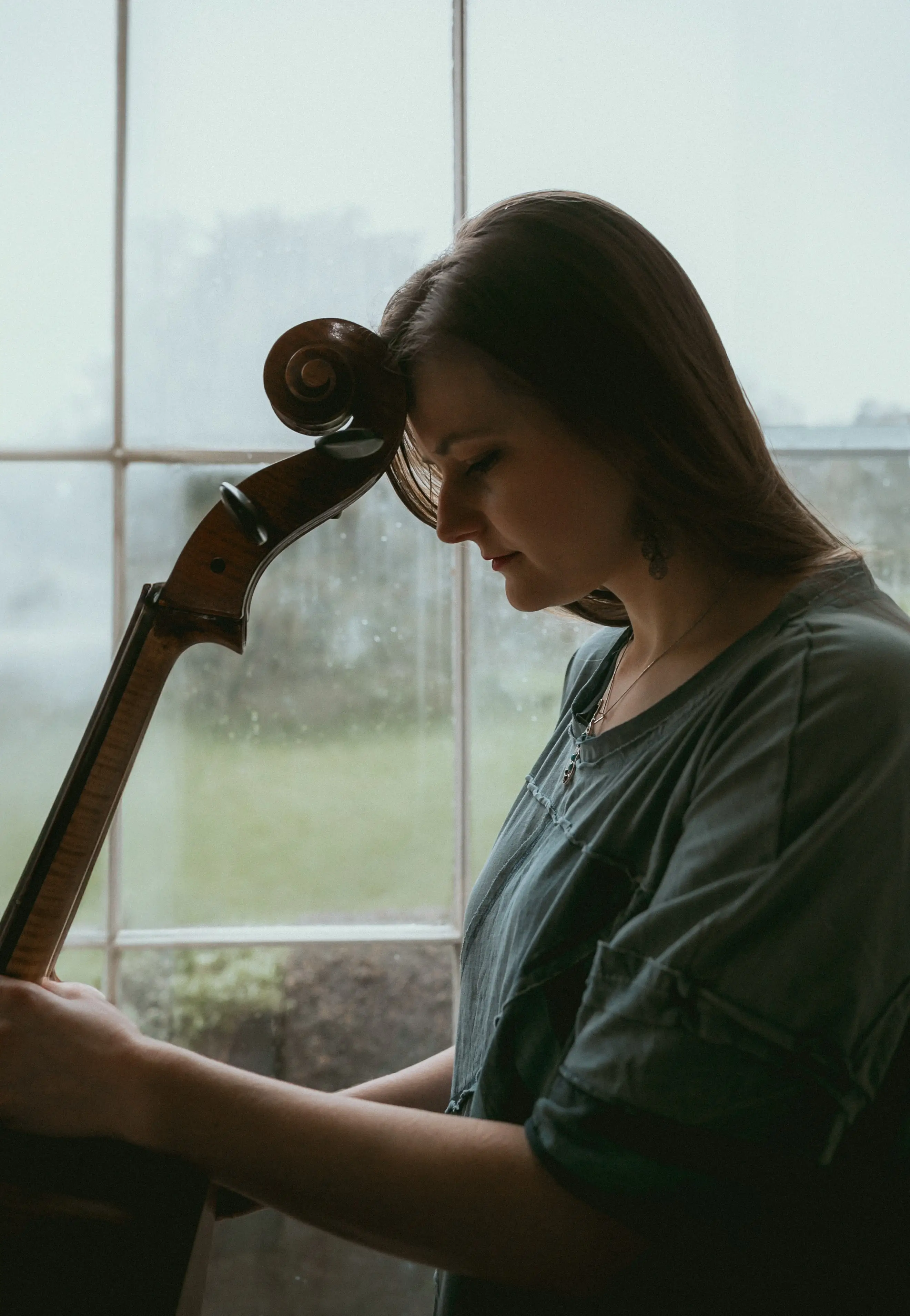 Cardiff wedding cellist resting her forehead on a cello scroll